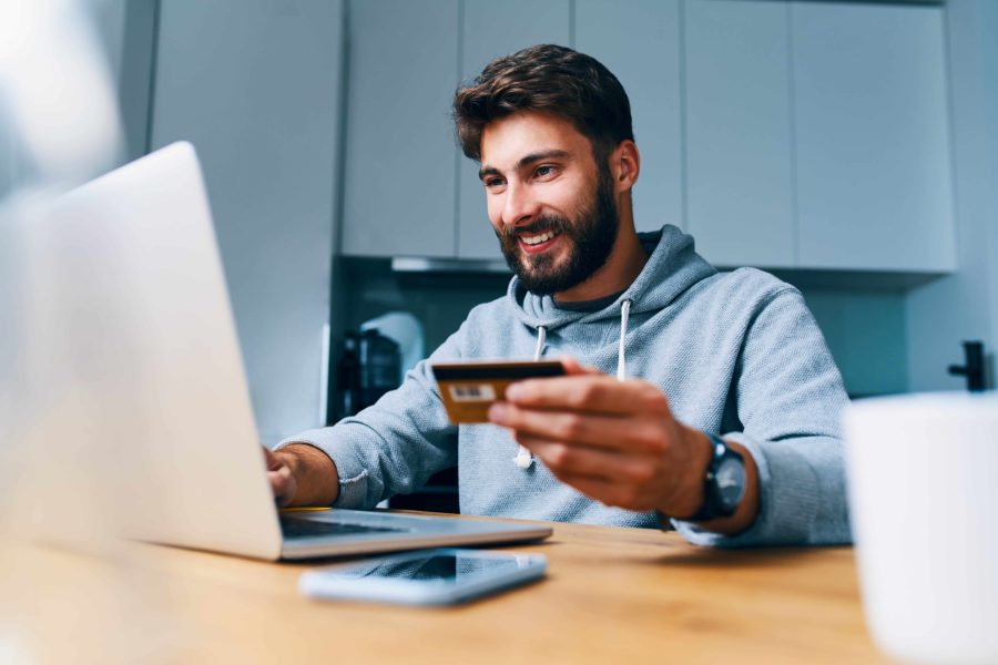 image of Cheerful young man paying bills online with credit card